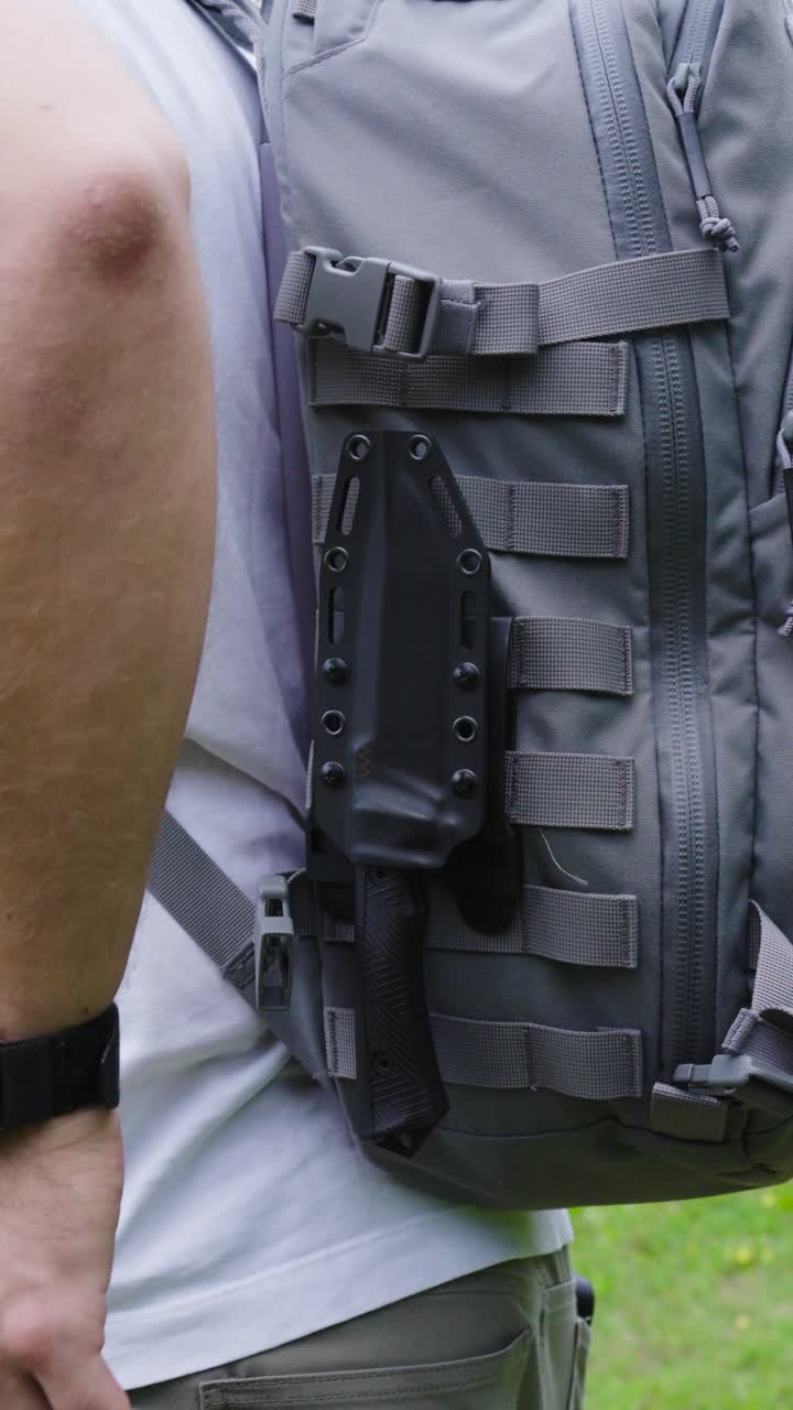 Vertical - person remove knife from holster attached to backpack, Czechia