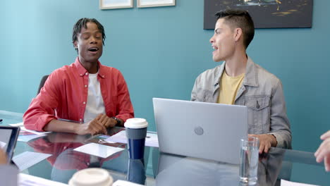 collaborating with laptop and documents, colleagues discussing ideas in office meeting