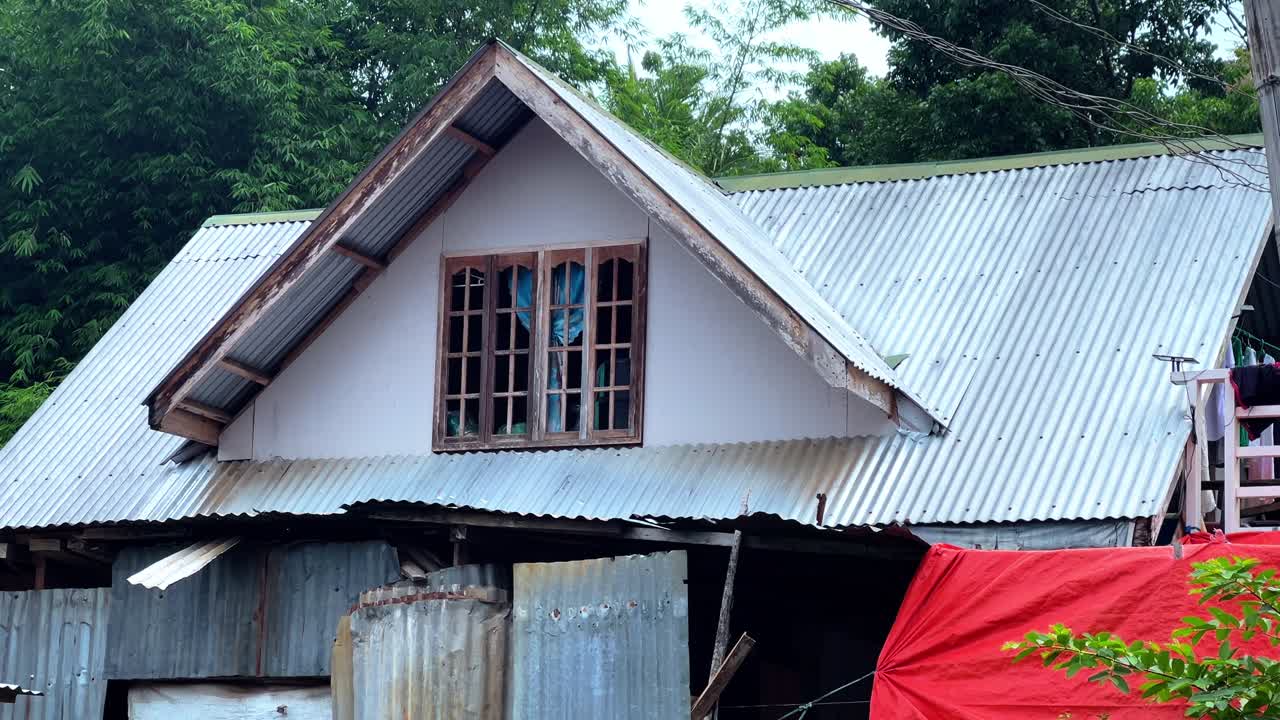 Close-up of a rural house with a corrugated metal roof and wooden framed window, ideal for architecture, housing, and countryside lifestyle projects