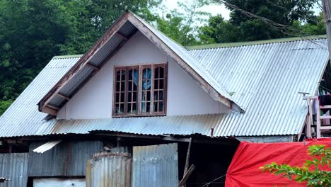 close-up of a rural house with a corrugated metal roof and wooden framed window, ideal for architecture, housing, and countryside lifestyle projects