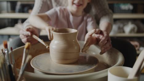 grandmother teaches her granddaughter working on a pottery rotating wheel