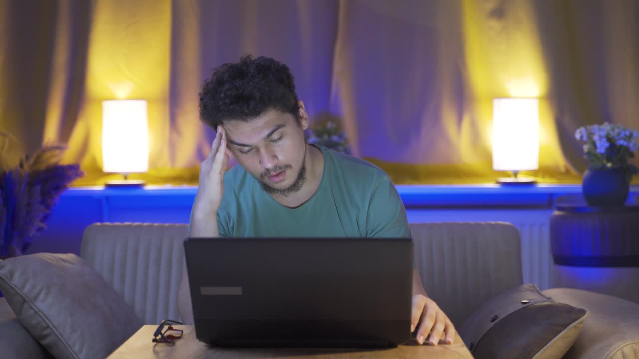 Man getting tired while using computer at night.