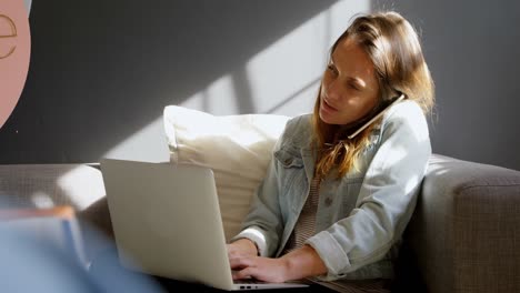Female jewelry designer talking on mobile phone while using laptop 4k