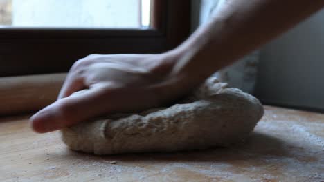 kneading the homemade pizza with wholemeal flour, shallow depth of field and natural light, close up shot