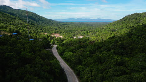 aerial backwards shot of path surrounded by tropical hills on koh phangan, thailand