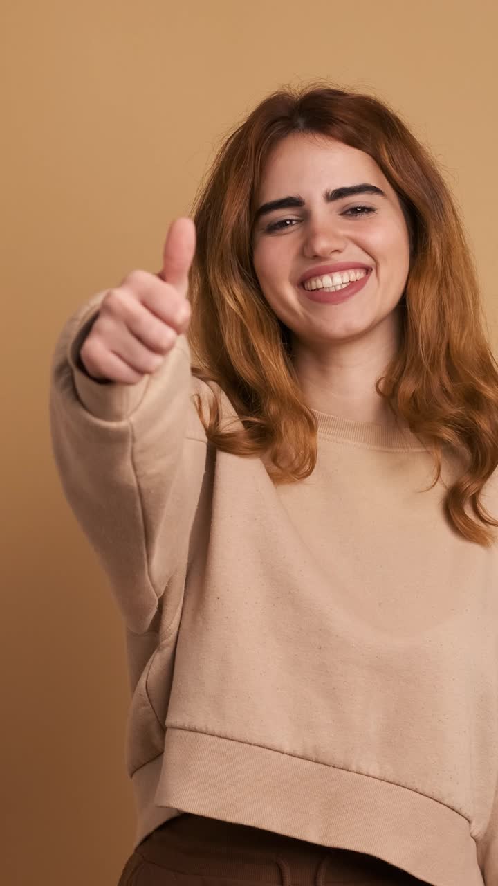 Happy young woman showing thumb up gesture. Vertical Footage