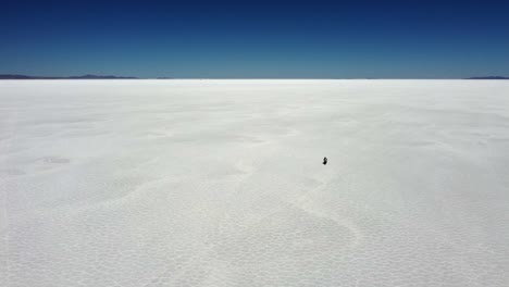 visão de alto ângulo: moto e piloto no vasto planalto de sal de uyuni, na bolívia