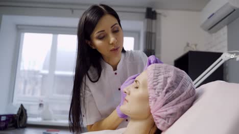 a beautiful cosmetologist in a white coat stands over the client and makes botox in the forehead area. modern skin rejuvenation procedure. wrinkle prevention
