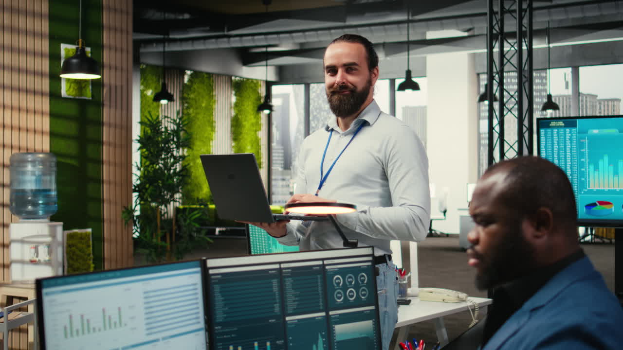 Vertical Video Male team leader monitoring analytics on a laptop in co working space