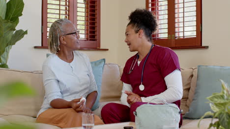 carer in scrubs comforting elderly woman at home, sharing warm conversation