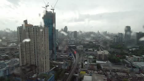la lluvia cae por la ventana. vista aérea. la lluvia fuera de la ventana de la sala de estar en la temporada de lluvias en bangkok, tailandia. la ventana exterior está borrosa por la lluvia del edificio de la ciudad y la carretera y el cielo.