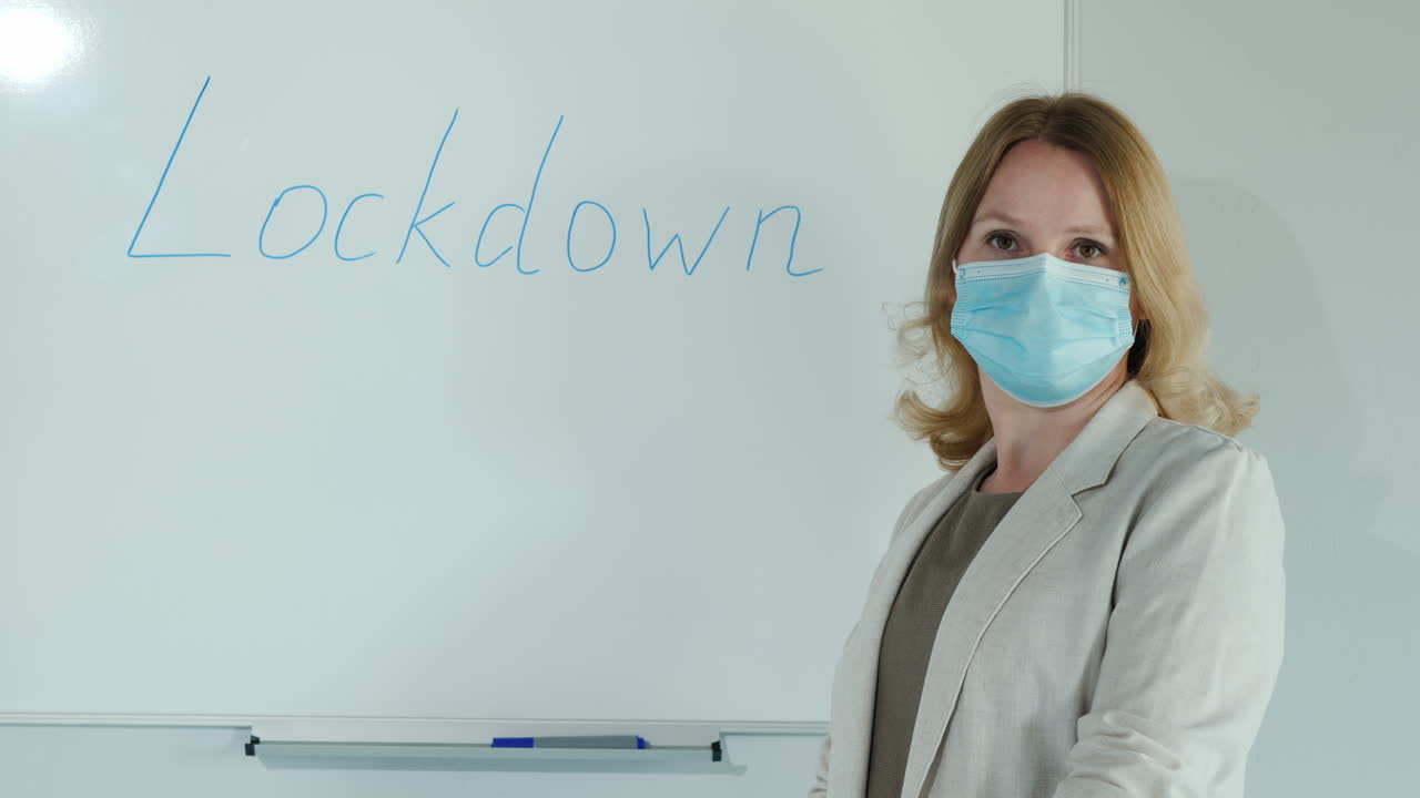 un maestro enmascarado se para en la pizarra con la palabra bloqueo escrita