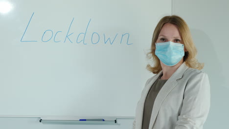 a masked teacher stands at the board with the word lockdown written