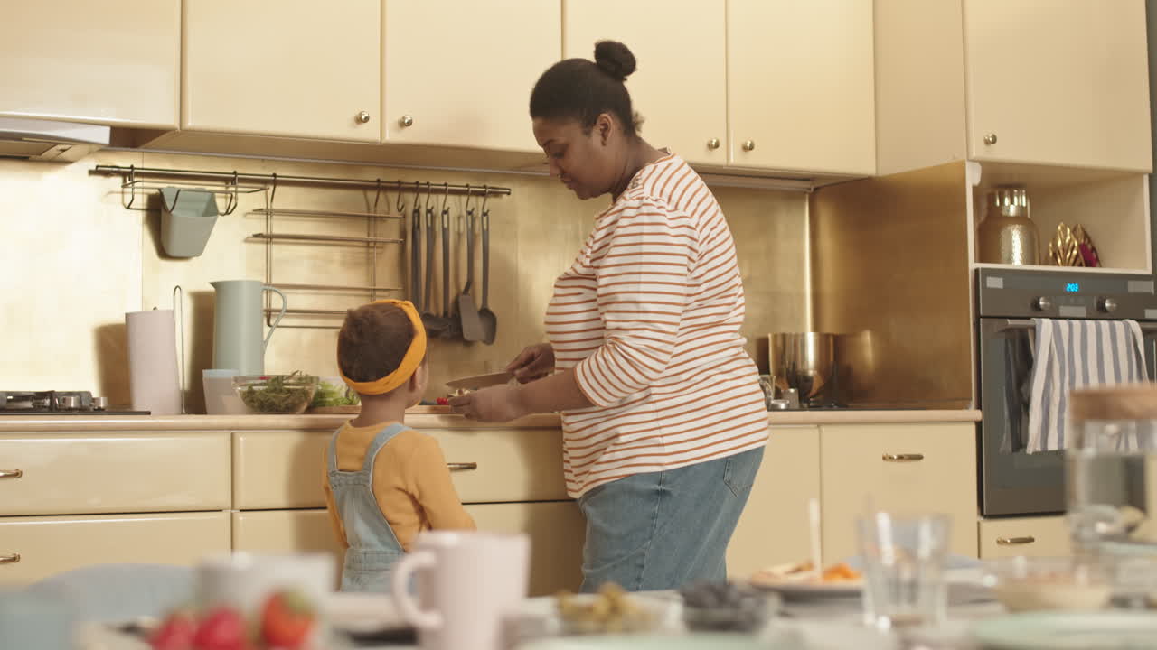 Piccola bambina africana che guarda la mamma cucinare