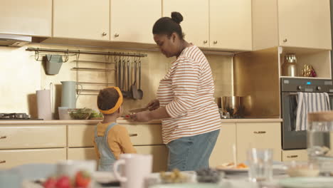 little african girl watching her mommy cooking