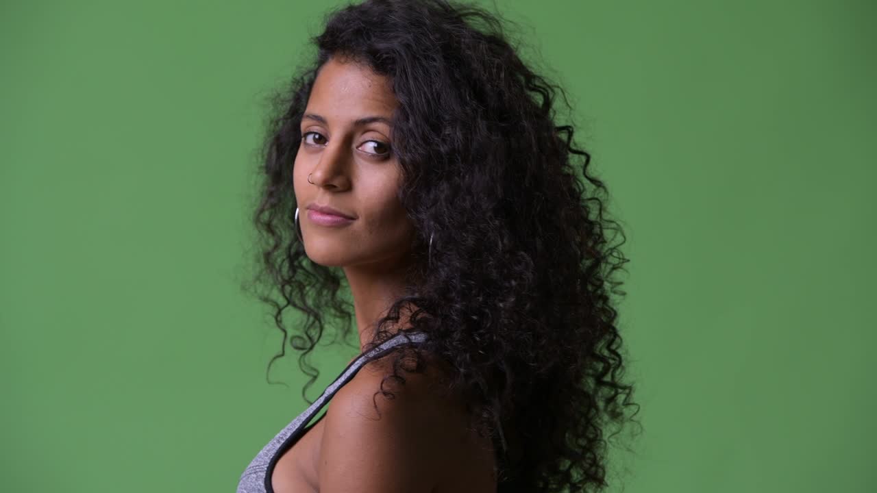 Young beautiful Hispanic woman with gym clothes looking back