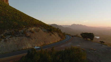 Um-Den-Bergrücken-Herumfliegen.-Verfolgung-Von-Autofahrten-Auf-Der-Straße-In-Der-Landschaft-Bei-Sonnenuntergang.-Südafrika