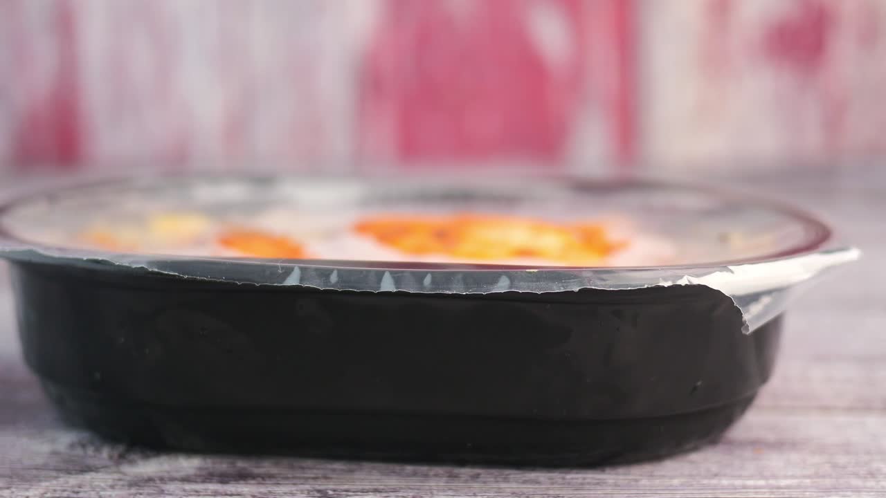 A sealed plastic food container on a wooden surface