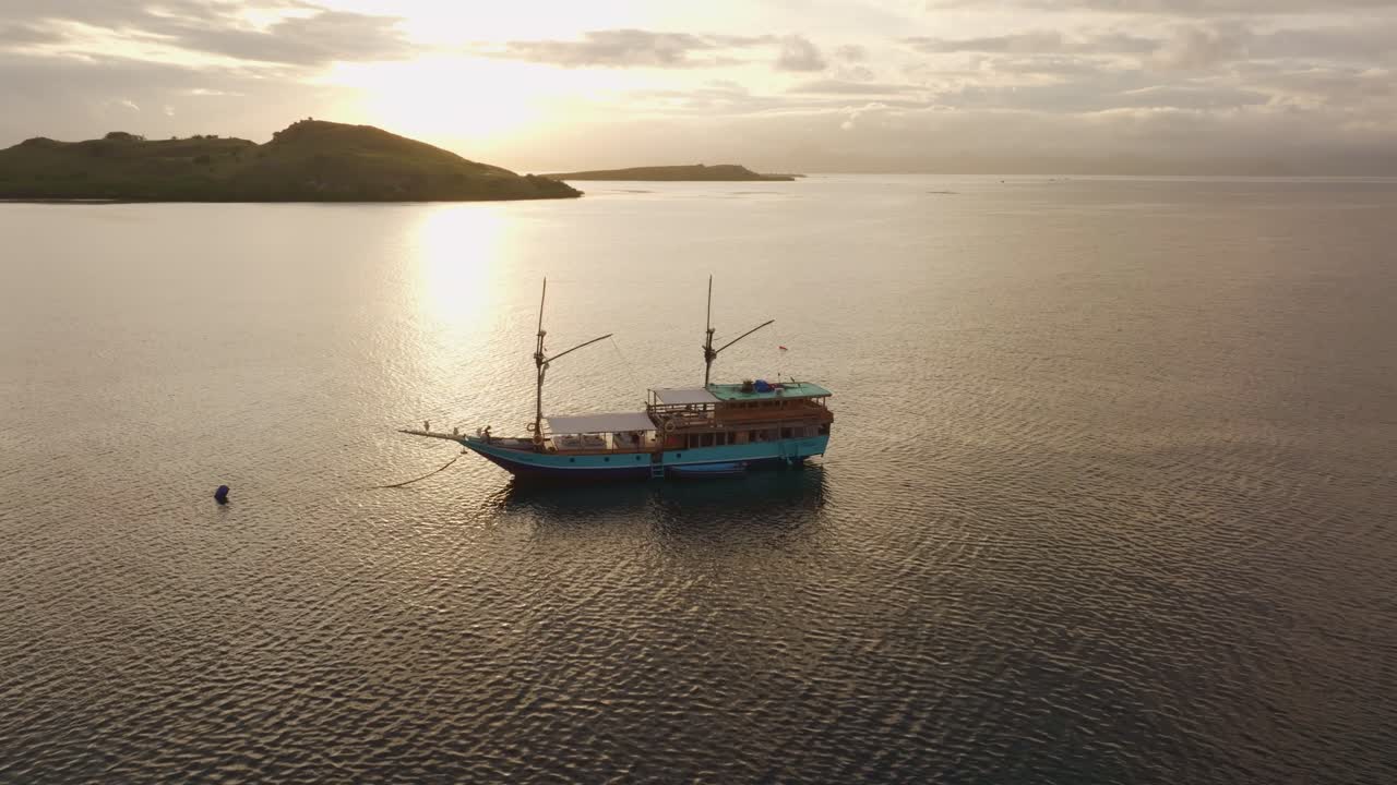 Alba dorata che si riflette sul mare con una barca galleggiante, Indonesia