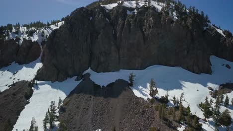 primer plano aéreo de una montaña de granito cubierta de nieve que sobresale hacia el cielo