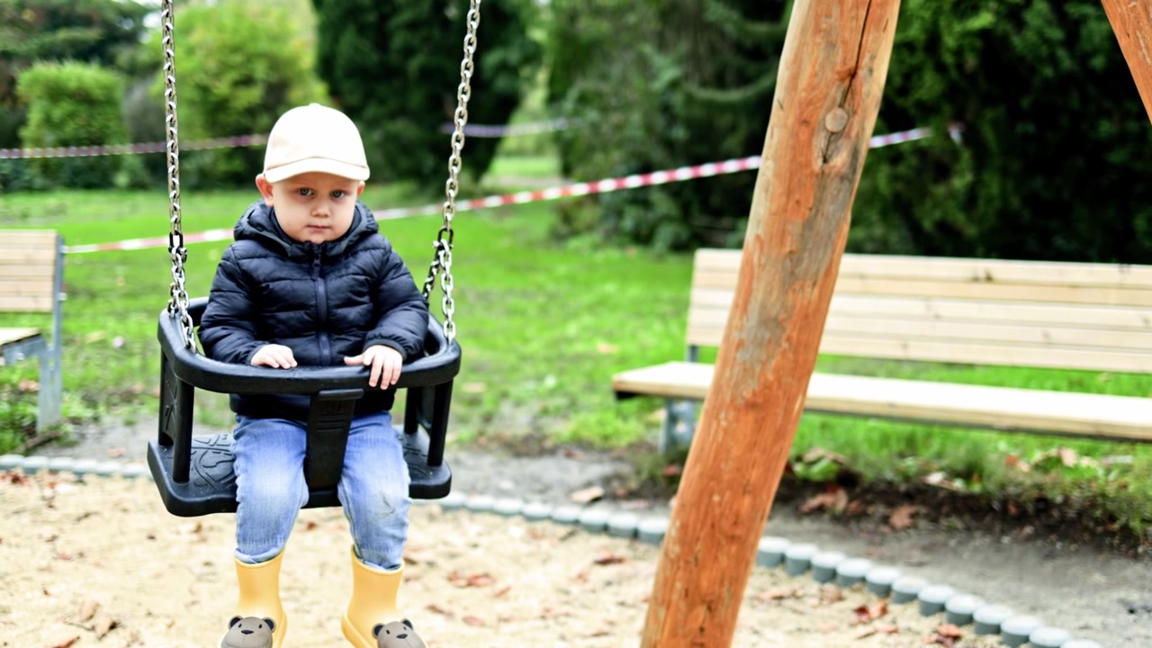 Adorabile bambino seduto su un'altalena al parco giochi