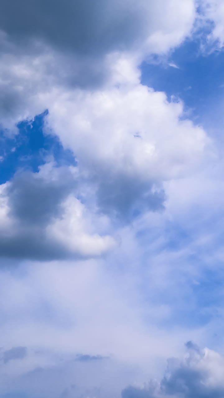 Flowing clouds in the sky. Blue summer rime lapse cloudscape. Vertical video