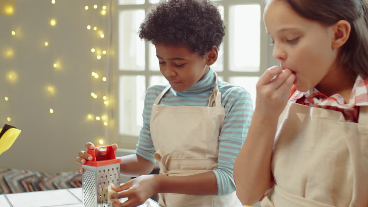 un niño y una niña rallando queso y hablando en la clase de cocina