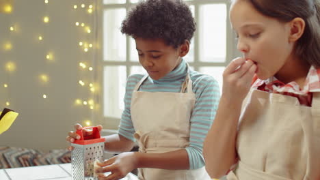 little boy and girl grating cheese and talking on cooking masterclass