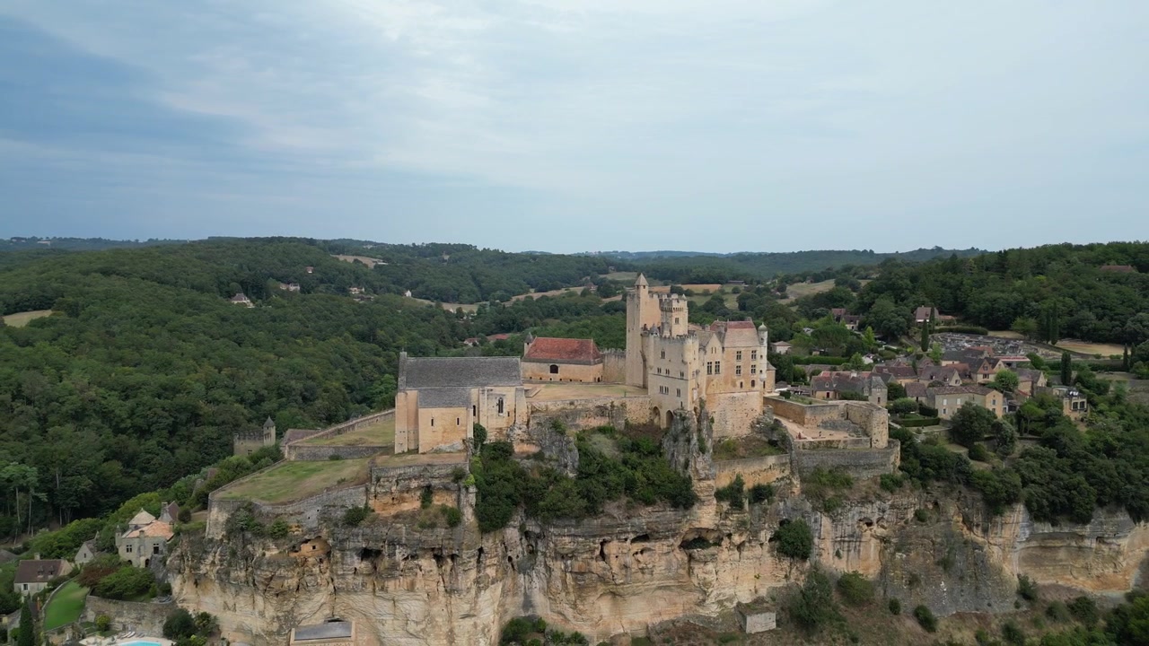 Vue aérienne par drone d'une petite ville médiévale ancienne dans la campagne française, située au sommet d'une montagne et entourée d'une forêt verte, avec un château à Beynac-et-Cazenac.