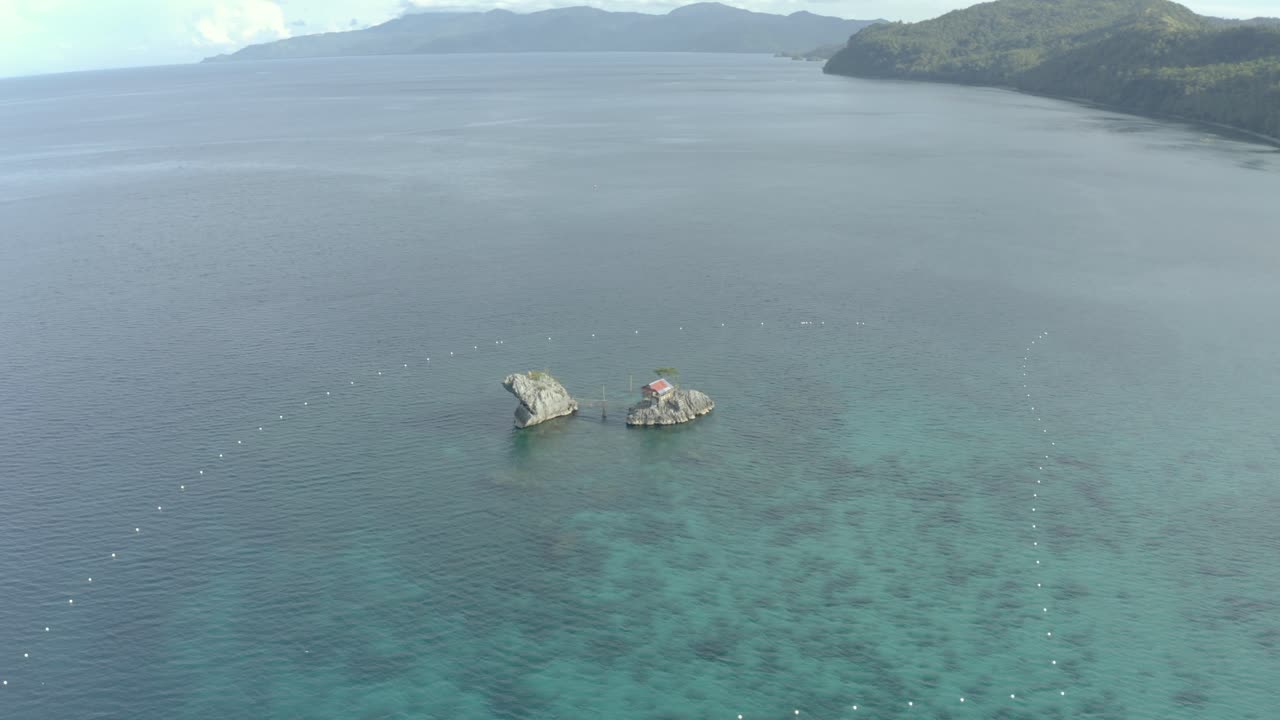 필리핀 열대 섬에 있는 잔잔한 푸른 바다로 둘러싸인 석회암 암석에 있는 오두막