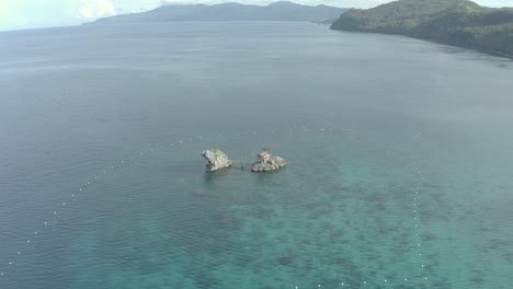 cottage on limestone rock formation surrounded with calm blue water of ocean in tropical island of philippines