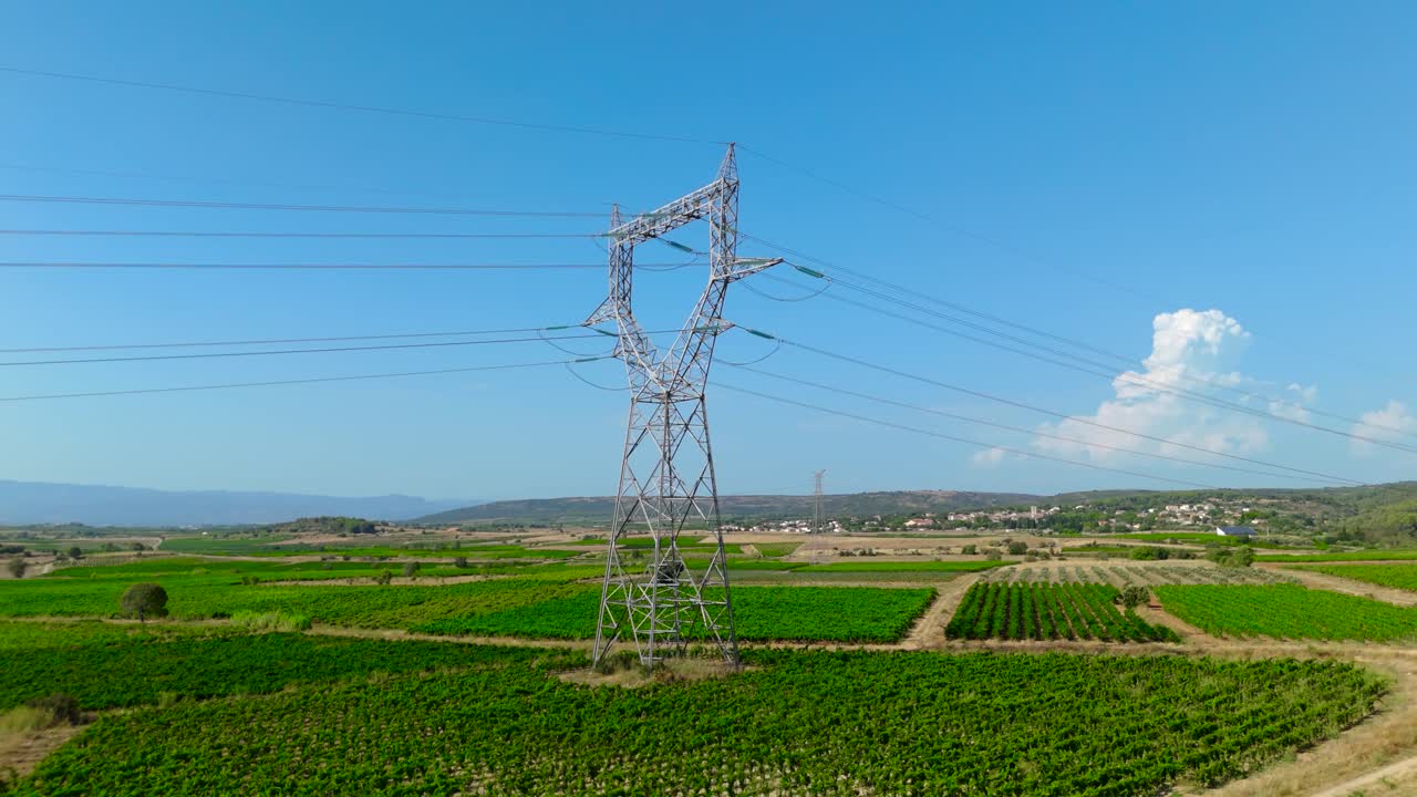 Electricity pylon standing tall in an expansive view of agricultural fields