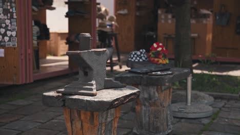 Iron-anvil-on-a-rustic-wooden-stand-at-Varaždin's-Market-of-Traditional-Crafts,-with-market-stalls-in-the-background