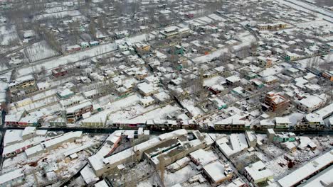 Toma-De-Drones-De-La-Ciudad-De-Skardu-Desde-Arriba,-Cubierta-De-Nieve-Y-Una-Carretera-Con-Coches.