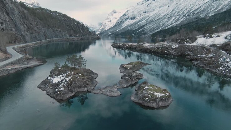 Piccole isole lacustri circondate da un'imponente catena montuosa in Norvegia, Loen, vista aerea.