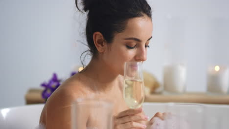 caucasian woman relaxing with champagne in bathtub