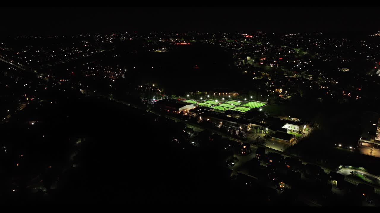 Distant soccer pitches and cityscape of Sheffield at night, wide drone shot