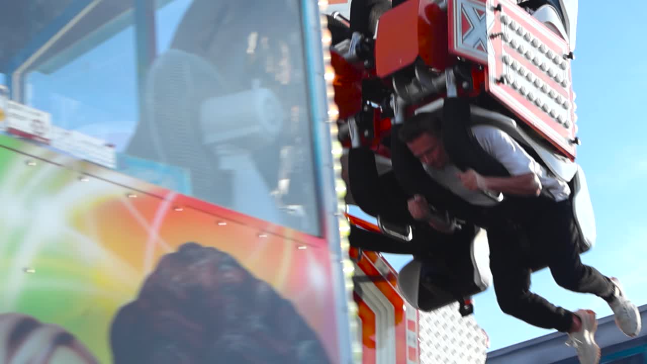 People Enjoying a Thrilling Amusement Park Ride Against a Blue Sky