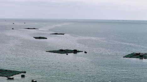 Aerial-backwards-shot-of-Vietnamese-style-fish-breeding-farms-on-sea