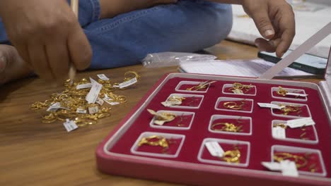 hallmarked 18k gold ornaments with barcodes, closeup, an indian shopkeeper managing stock of gold ornaments