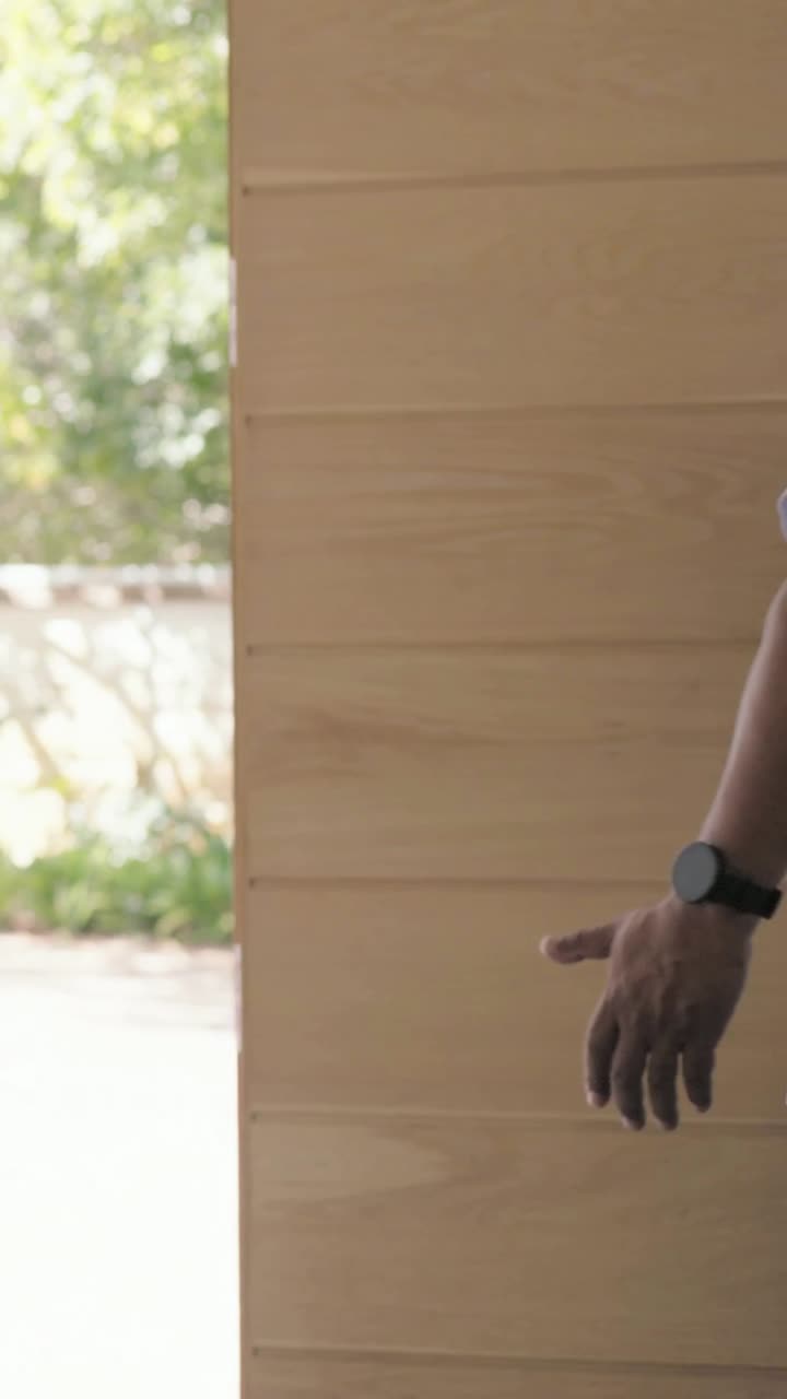 Vertical video: Greeting host shaking carer on arrival in scrubs at front door, guiding in with bag