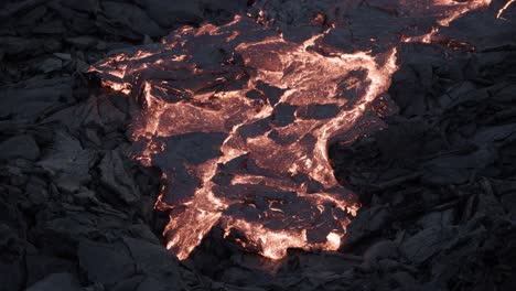 lava viscosa de movimiento lento en la superficie de roca basáltica oscura por la noche
