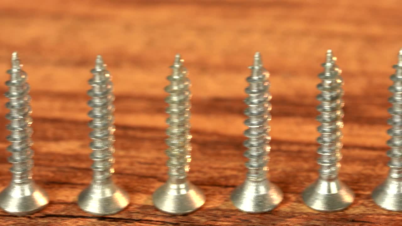 tornillos de acero en una mesa de madera. producción de tornillos, montón de detalles metálicos, primer plano