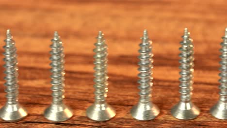 steel screws on wooden table. screw production, heap of metal details, close up shot