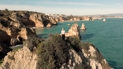 AERIAL:-Girl-is-standing-on-the-cliffs-in-Portugal-enjoying-a-beautiful-view