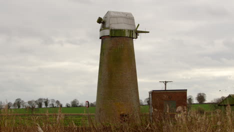 strzał boczny patrzący przez trzcinę na opuszczony norfolk broads wiatrak pompa wody na rzece mrówka w pobliżu ludham most