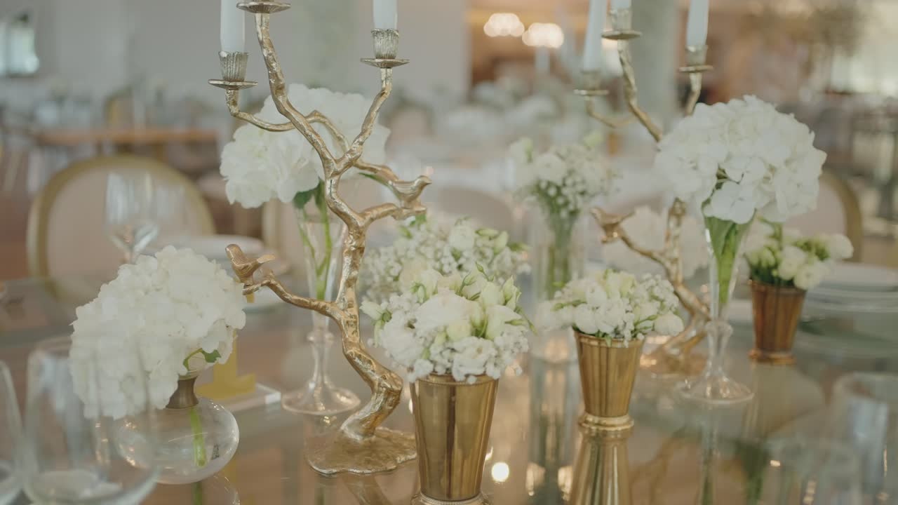 Luksuriøs bryllupsborddekor med hvite blomsteroppsatser og lys