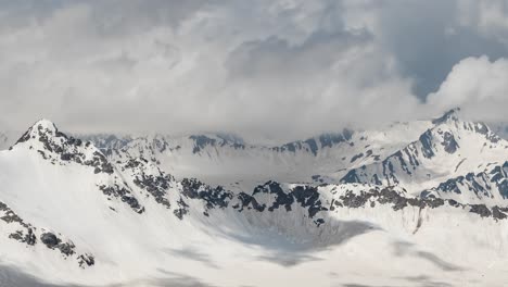 air flight through mountain clouds over beautiful snow-capped peaks of mountains and glaciers.