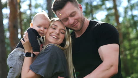 happy family embracing. couple holding their little baby son standing in the nature backdrop.
