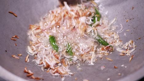 stir-frying onions and green chillies in a wok